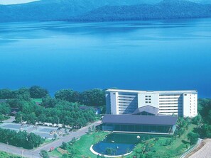 Un grande edificio con un parcheggio e un lago sullo sfondo.