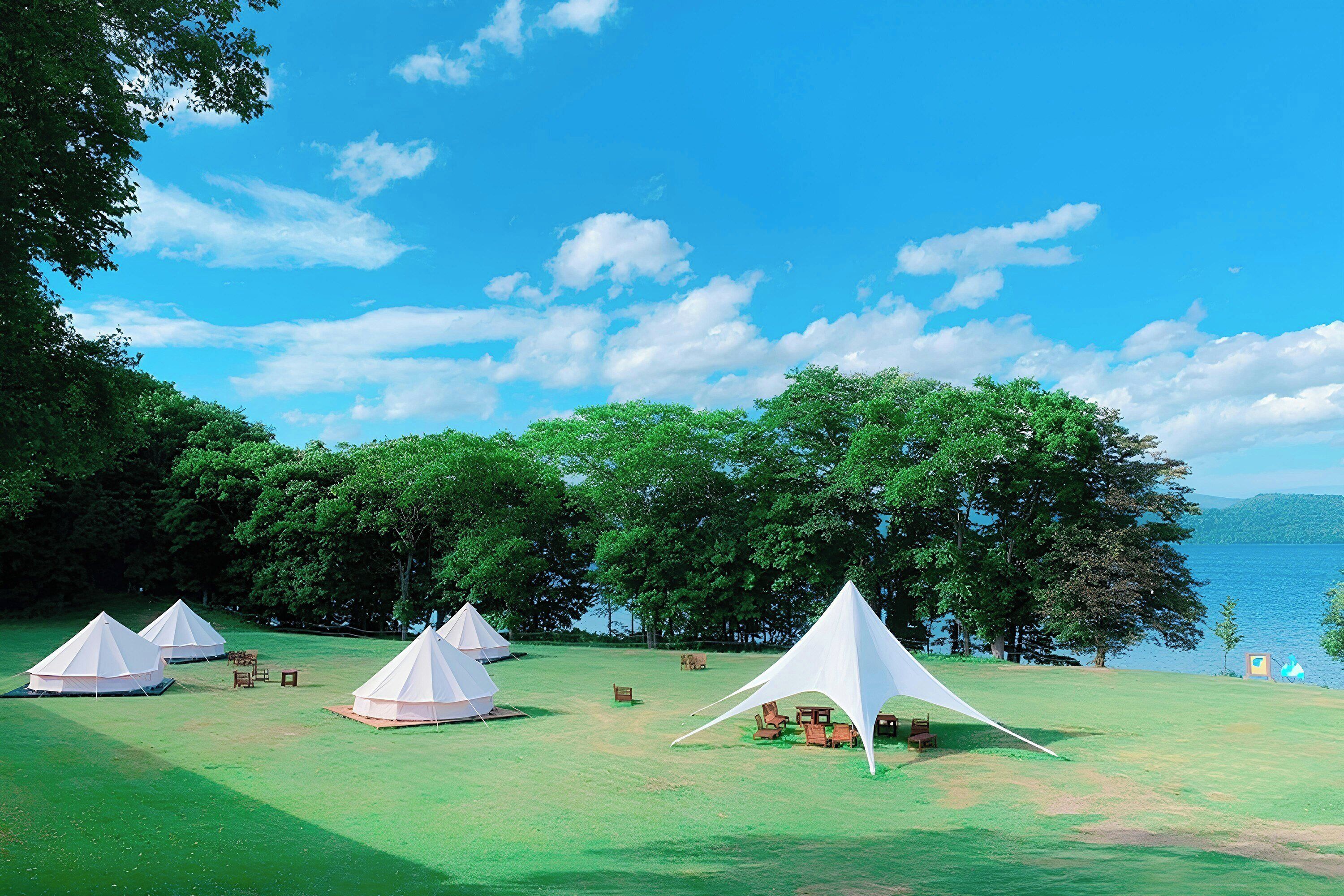 A campsite with tents, picnic tables, and a lake view.