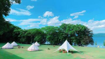 A campsite with tents, picnic tables, and a lake view.