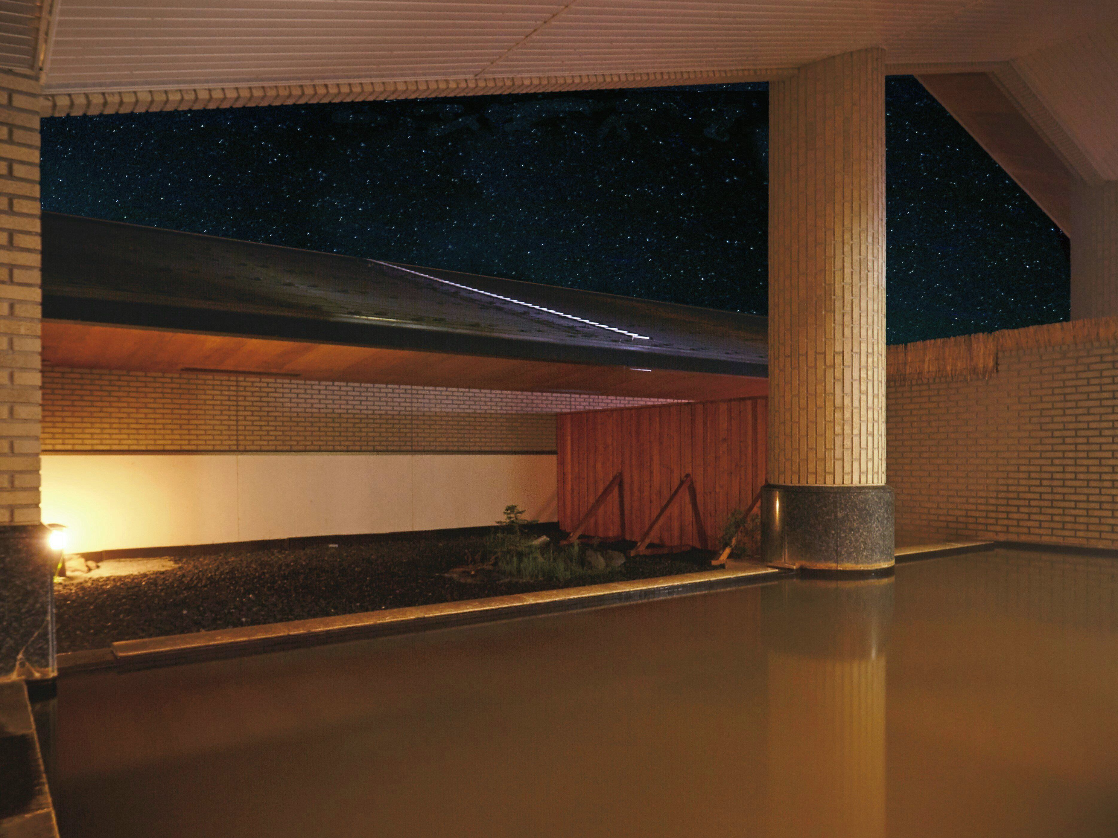 A building with a starry night sky visible through a skylight, brick walls, and a concrete floor.