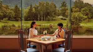 A dining table with chairs, a view of a lake, and a forested hill in the background. - Kussharo Prince Hotel (Teshikaga)