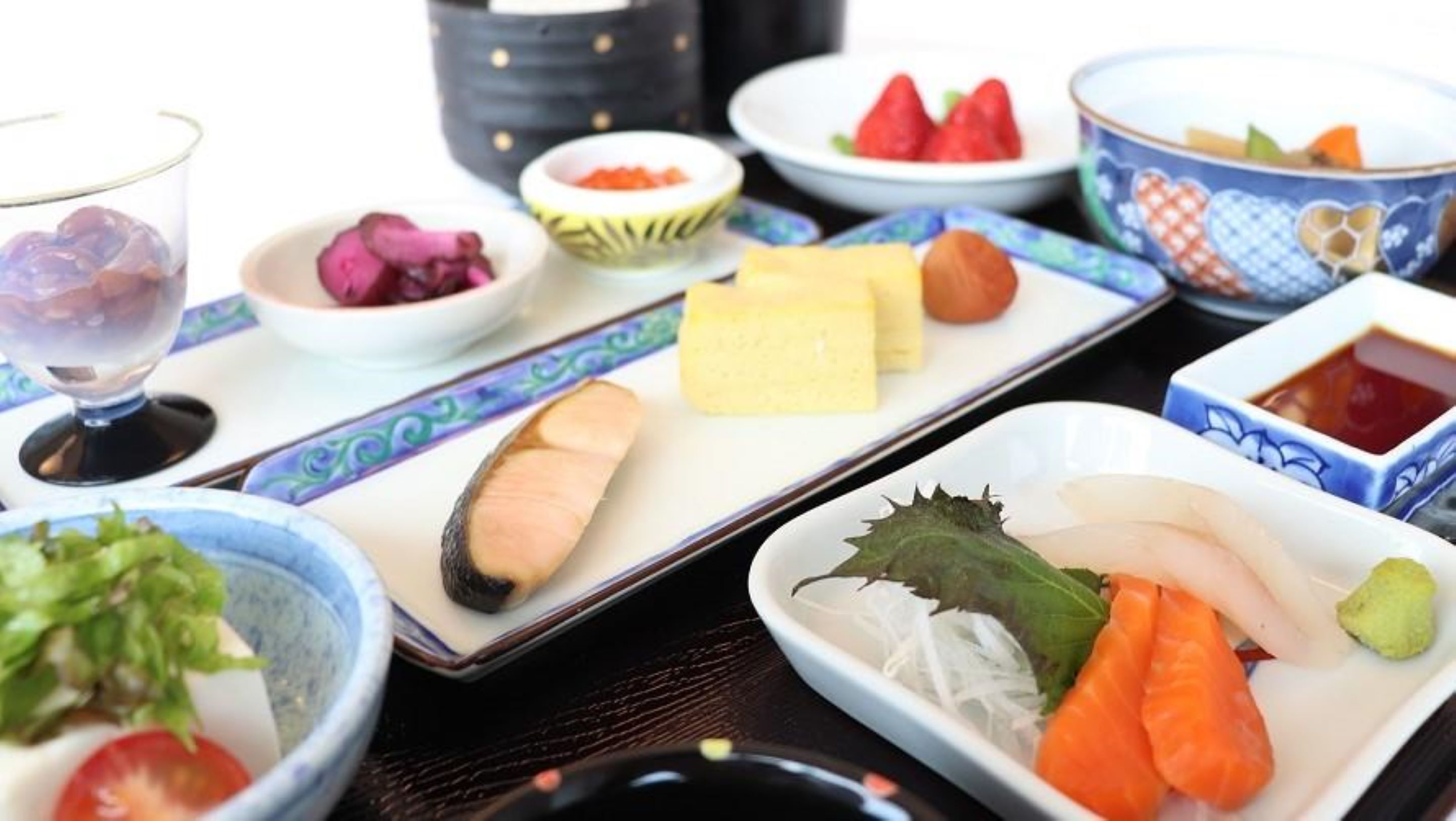 Variedad de platos que incluyen sushi, sashimi y verduras sobre una mesa.