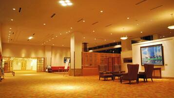 A spacious lobby with a carpeted floor, seating area with chairs, a reception desk, and a large framed artwork on the wall.