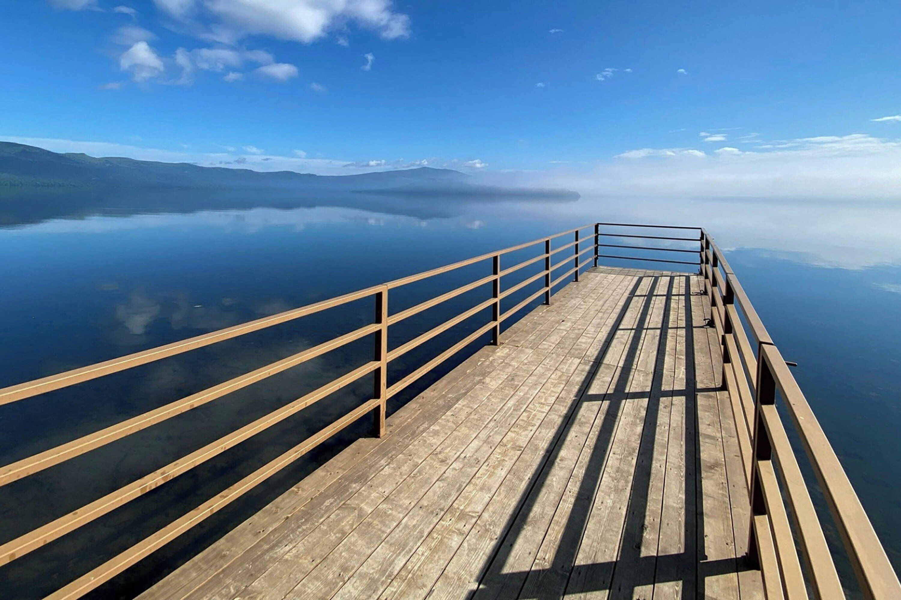 A wooden pier extending over calm water with a clear sky above.