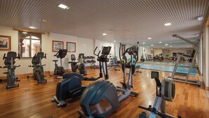 A gym with various exercise equipment, a pool, and wooden flooring. - The Residences Vilamoura (Loulé)