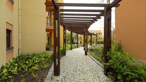 A corridor with a wooden pergola, cobblestone path, and greenery. - The Residences Vilamoura (Loulé)
