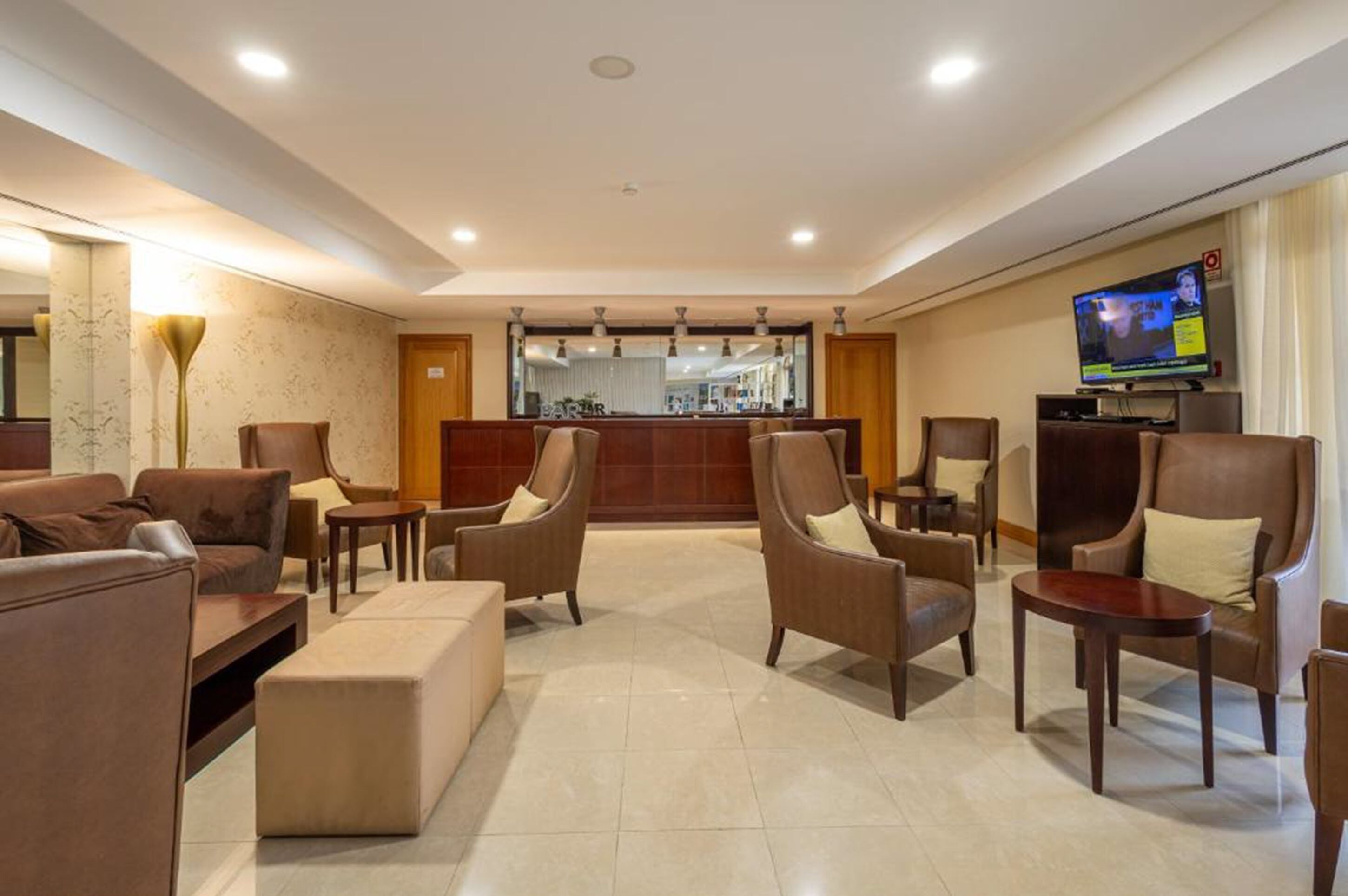 Een hotel lobby met een bar, zitgedeeltes en een televisie.