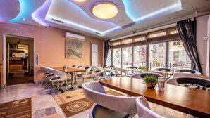 A modern dining area with a long table, multiple chairs, and a large window with a view. - Hotel Danubia Gate (Bratislava)