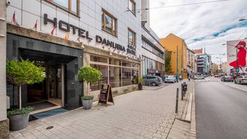 A hotel named "HOTEL DANUBIA GATE" with a modern facade, large windows, and a visible entrance.