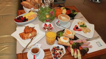 A breakfast tray with croissants, fruit, eggs, and coffee.