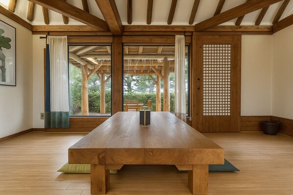 A room with a wooden table, large windows, a tatami mat, and a shoji screen.