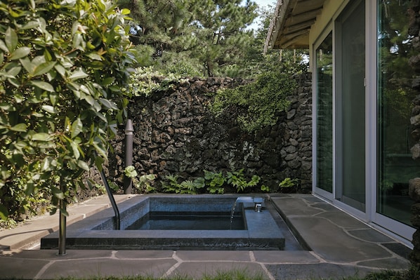 A stone wall, a small water feature, and a glass door. - Seaes Hotel & Resort (Seogwipo)