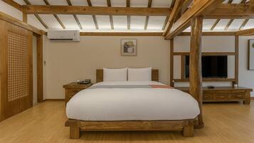 Ein Schlafzimmer mit einem hölzernen Bettgestell, einem Nachttisch, einer Klimaanlage und einem Fernseher auf einem Holzständer.