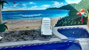 Area piscina con vista sull'oceano e atmosfera tropicale.