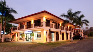 Un hotel su due piani con reception, balconi e area parcheggio.