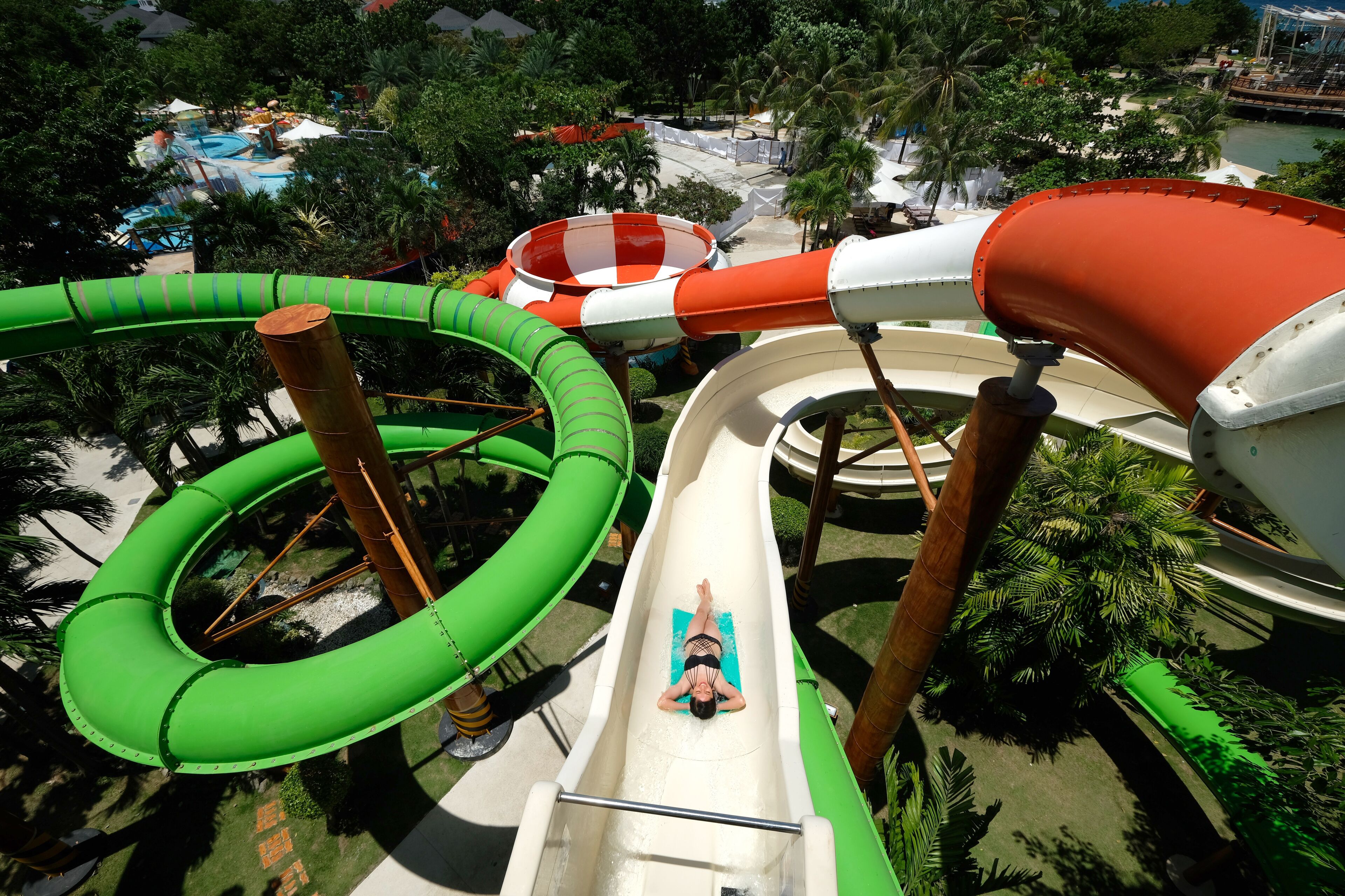 A water park with multiple slides and a pool area surrounded by palm trees.