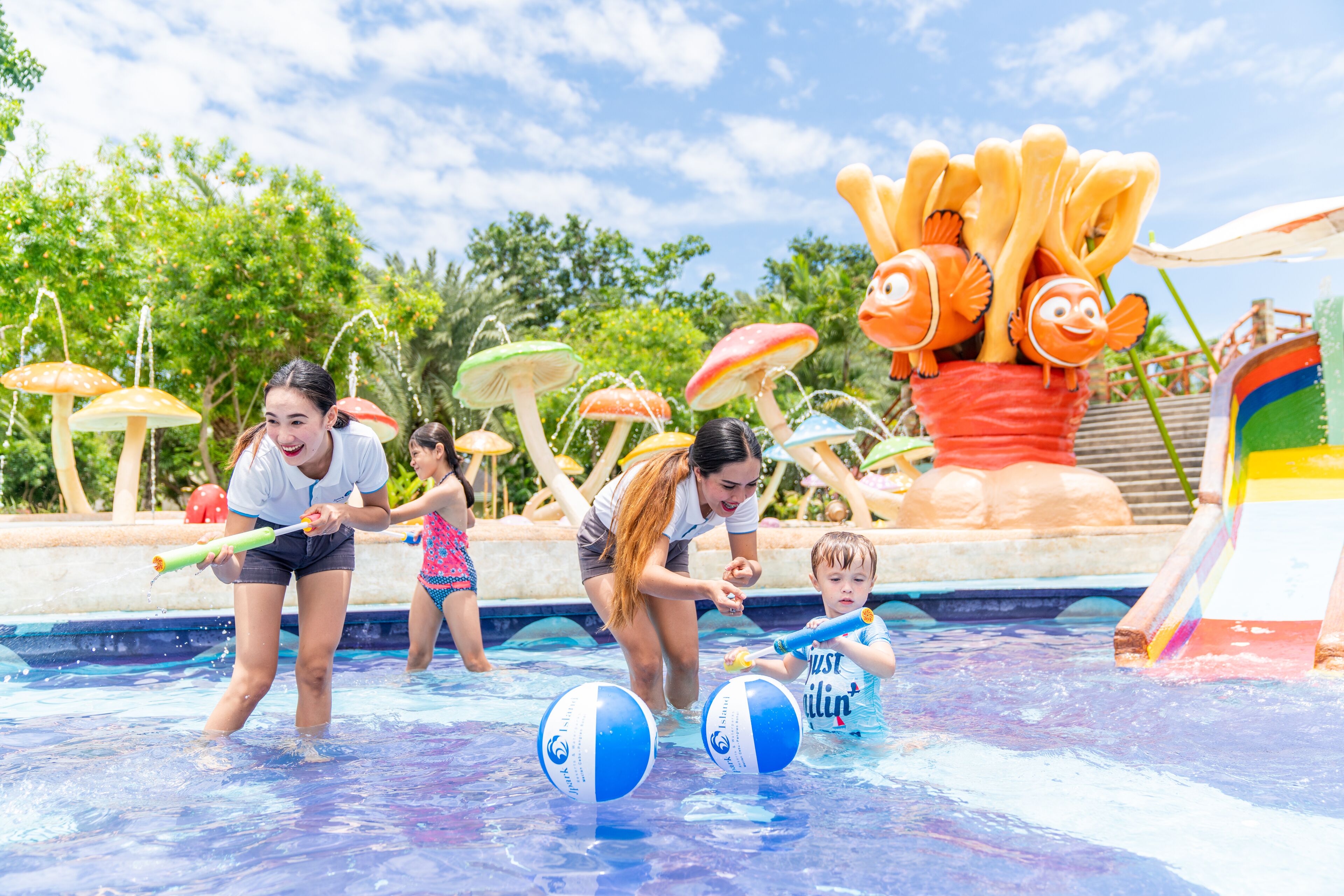 A swimming pool with water play features, including water jets and a large fish decoration.