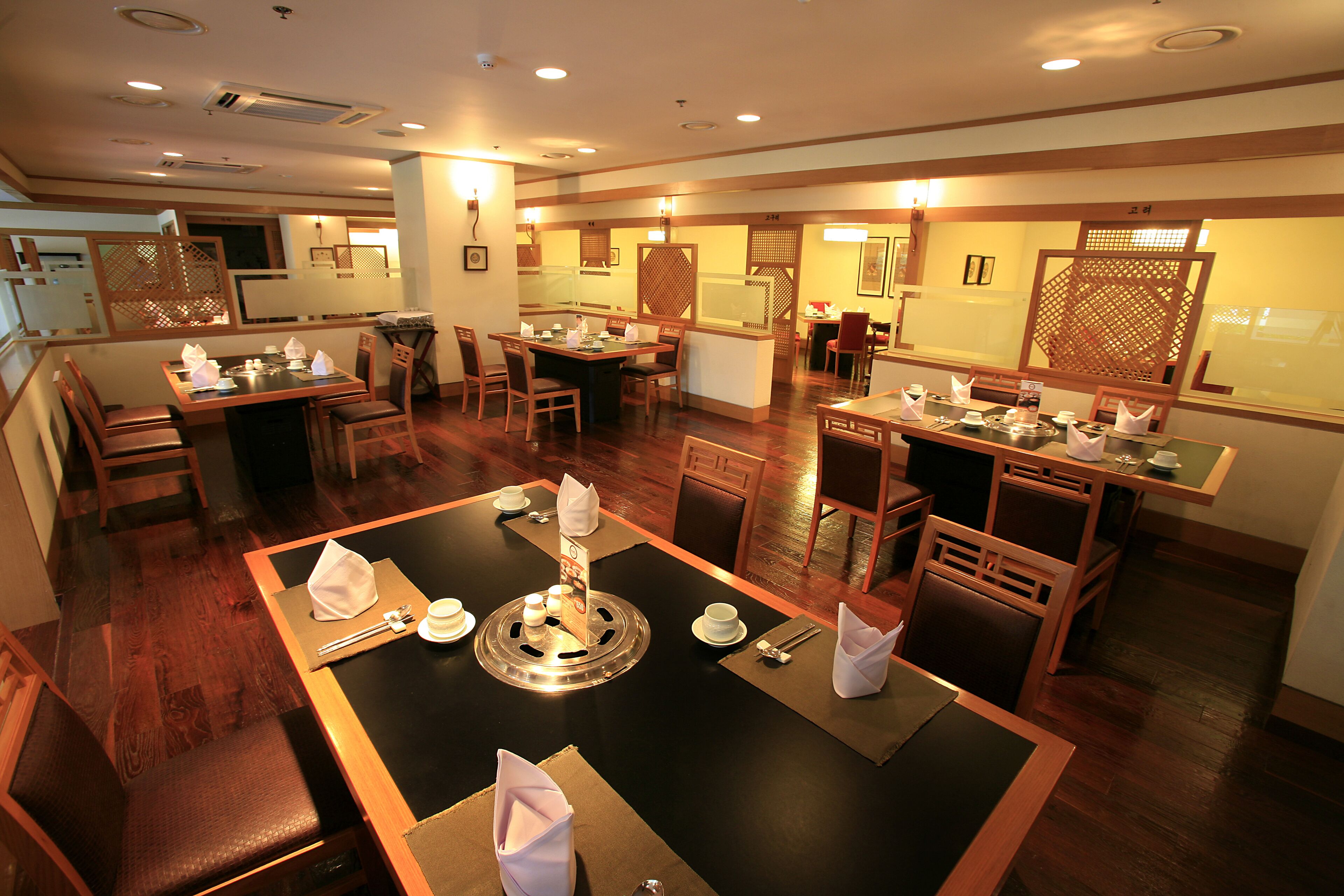 A restaurant with multiple dining areas, wooden furniture, and a central table with a decorative centerpiece.