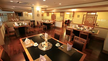 A restaurant with multiple dining areas, wooden furniture, and a central table with a decorative centerpiece.