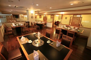 A restaurant with multiple dining areas, wooden furniture, and a central table with a decorative centerpiece.