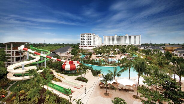 Un resort con una gran piscina, toboganes acuáticos y un hotel al fondo.