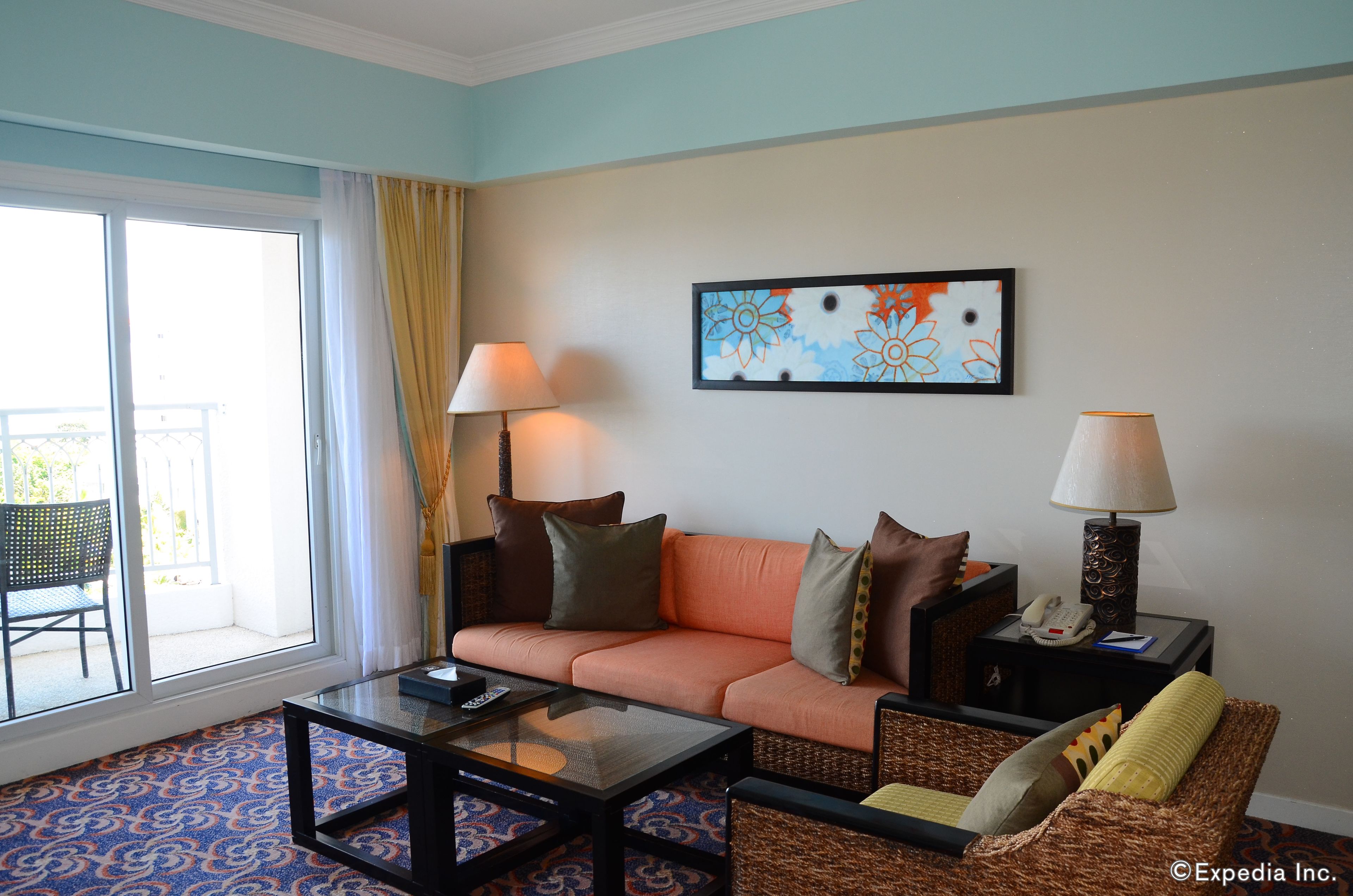 A living room with a sofa, two side tables with lamps, a coffee table, and a large window with curtains.