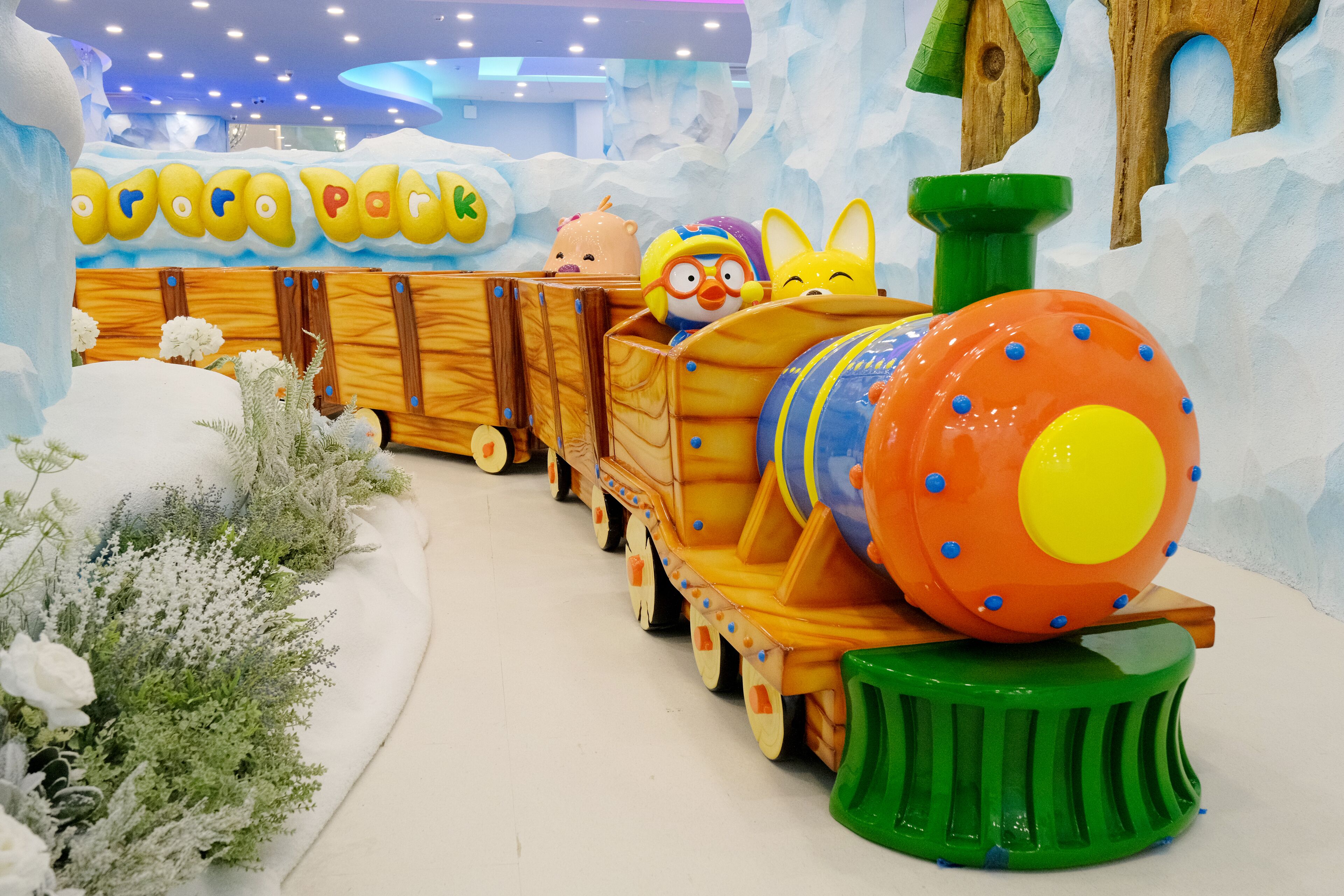 A colorful train ride through a snowy landscape with wooden train cars and a large orange engine.