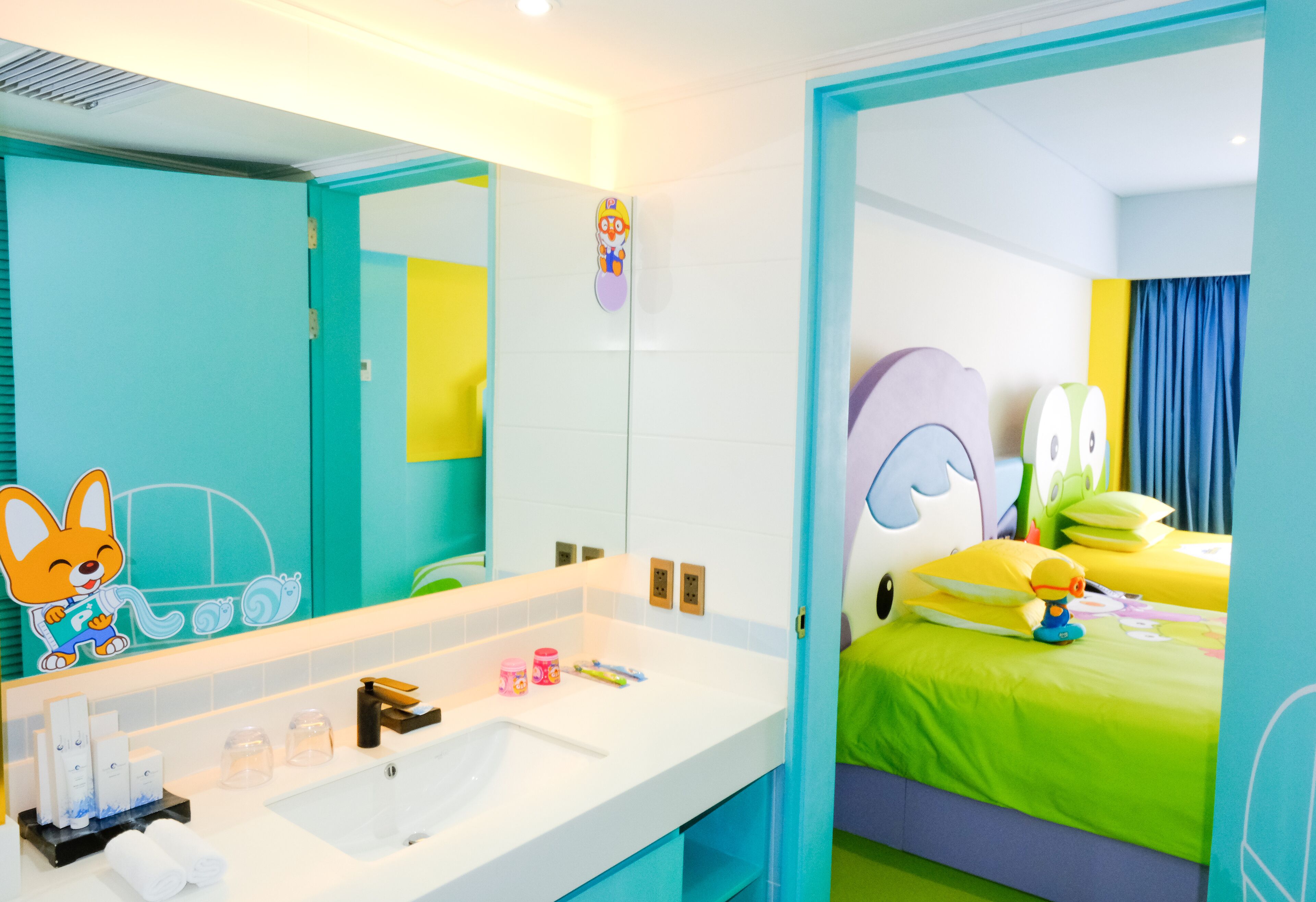 Habitación infantil con un espejo grande, un lavabo y una cama con ropa de cama colorida.
