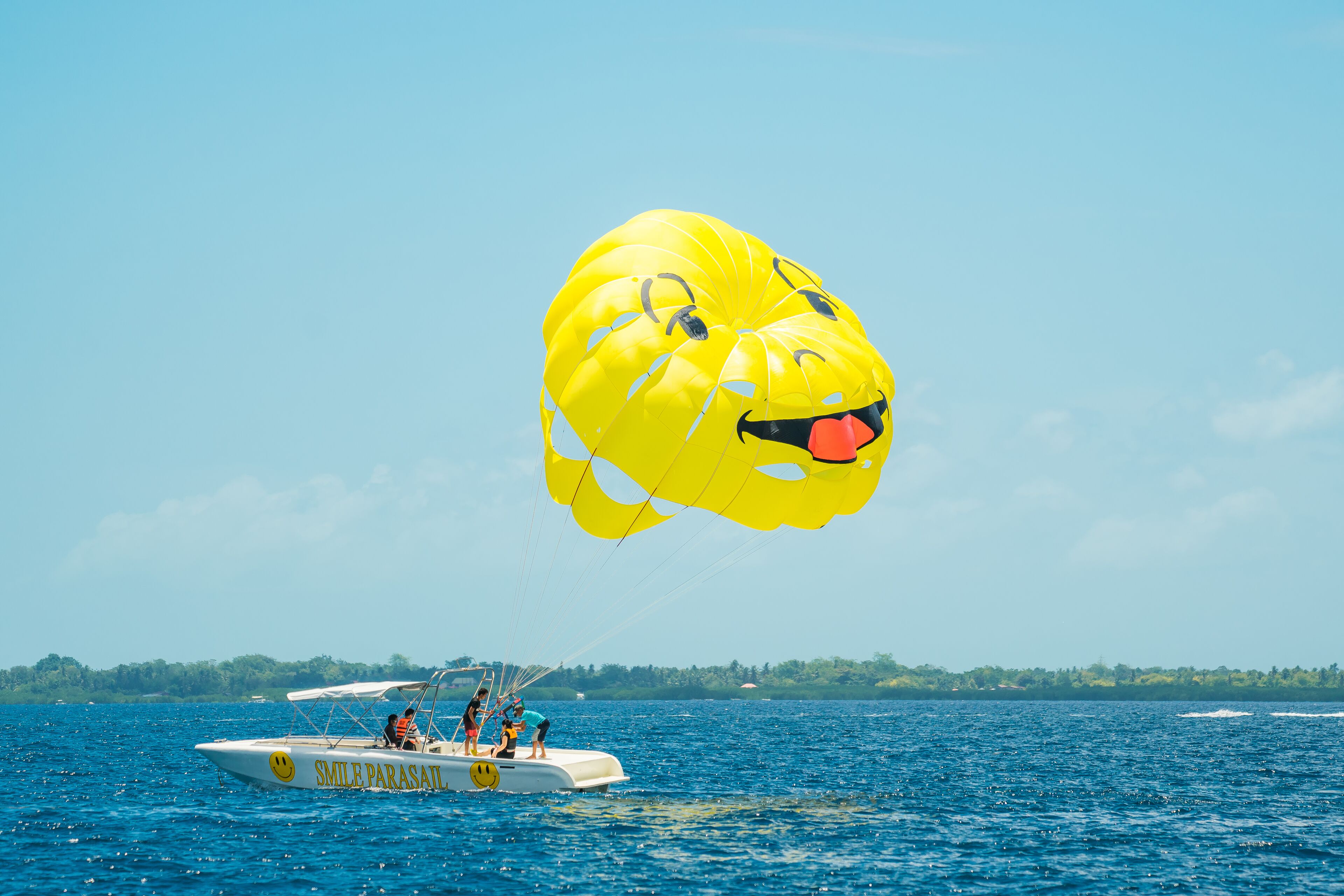 Un parasail con un diseño de carita sonriente sobre una extensión de agua.