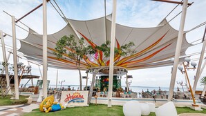 Un restaurante frente al mar con un área de estar al aire libre techada, un escenario para espectáculos y un letrero que dice "Havana by the Sea".