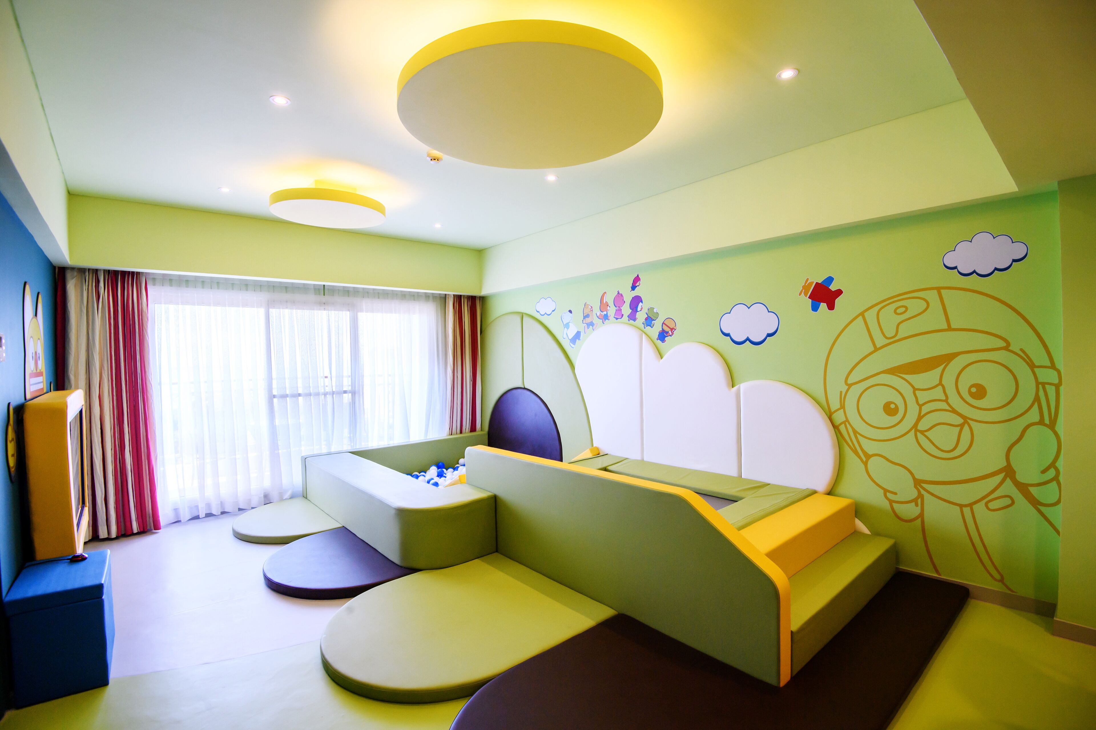 A modern bedroom with a curved bed, built-in seating, and playful wall art.