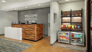 A reception area with a wooden reception desk, a sign reading "WELCOME TO THE CENTRAL STATE," and a snack bar with various snacks and beverages.