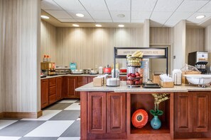 A kitchen with wooden cabinets, a countertop with various appliances, and a sign that reads "HAPPY BREAKFAST STARTS HERE".