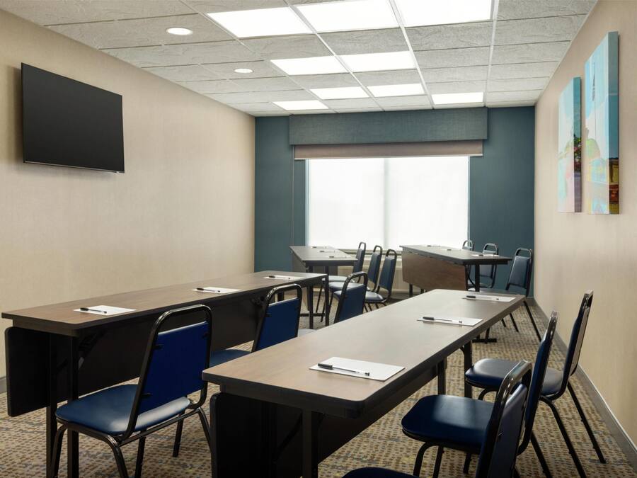 A conference room with a large table, chairs, a flat-screen TV, and artwork on the walls.