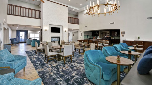 A spacious hotel lobby with multiple seating areas, a bar, and a high ceiling with a chandelier. - Homewood Suites by Hilton Palm Desert (Palm Desert)