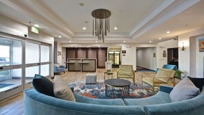 A modern lobby with a blue sofa, a patterned rug, and a chandelier. - Homewood Suites by Hilton Palm Desert (Palm Desert)