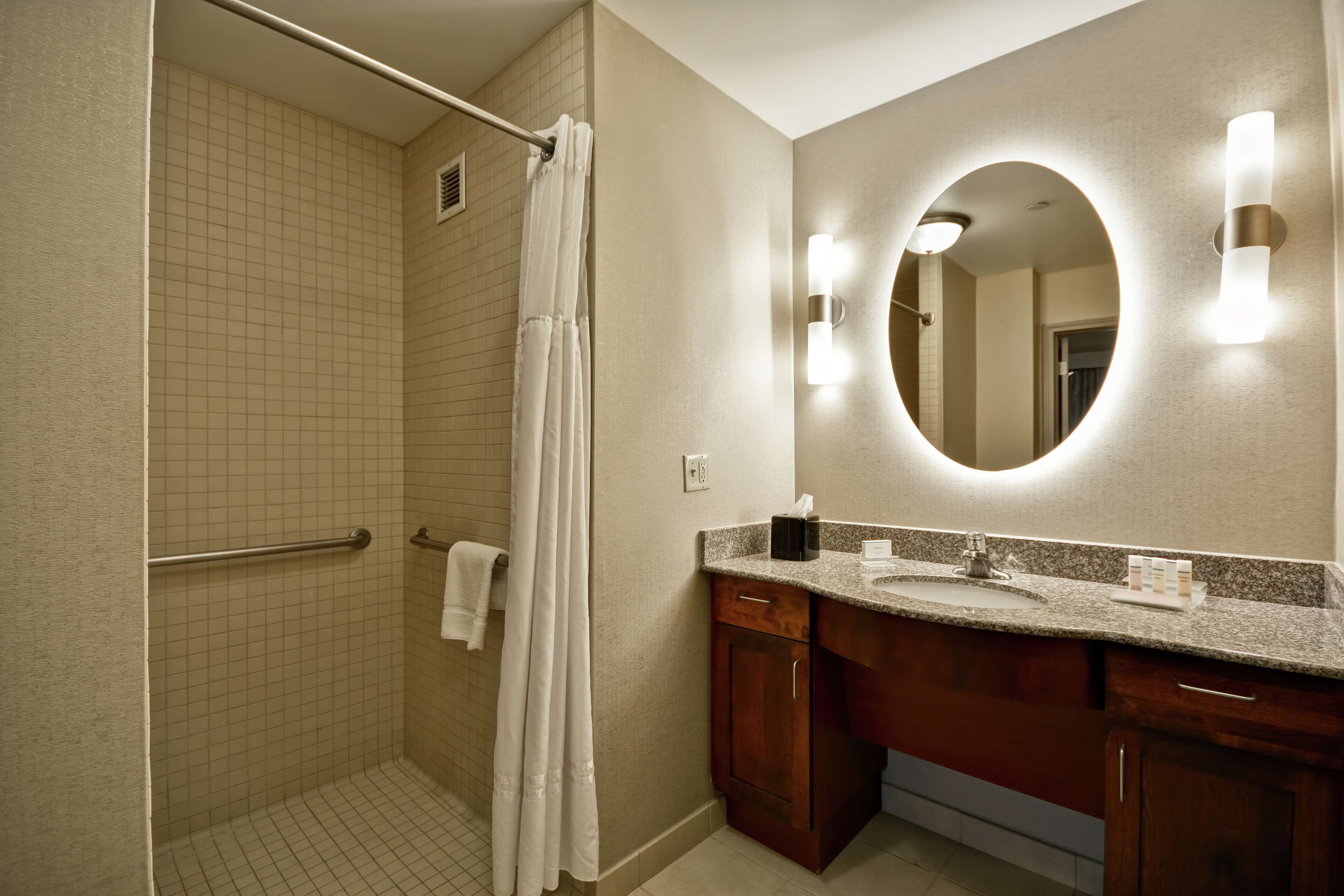 Une salle de bain avec une douche à l’italienne, un meuble-lavabo et un miroir agrémenté d’appliques murales.