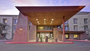 A modern hotel entrance with a unique architectural design, featuring a large overhang and a sign reading "Homewood Suites Hilton." - Homewood Suites by Hilton Palm Desert (Palm Desert)