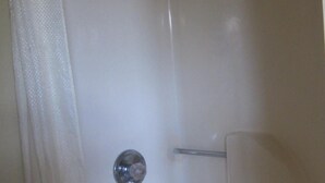 A white shower with a chrome faucet, a glass-enclosed showerhead, and a chrome handle.