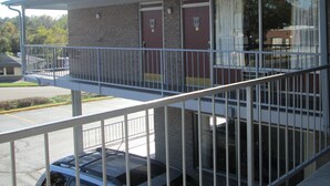 A building with two doors, a covered balcony, and a parking lot.