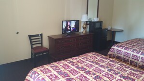A hotel room with a bed, a TV on a dresser, a chair, a desk, and a lamp. - Budgetel Inn and Suites (Rockingham)