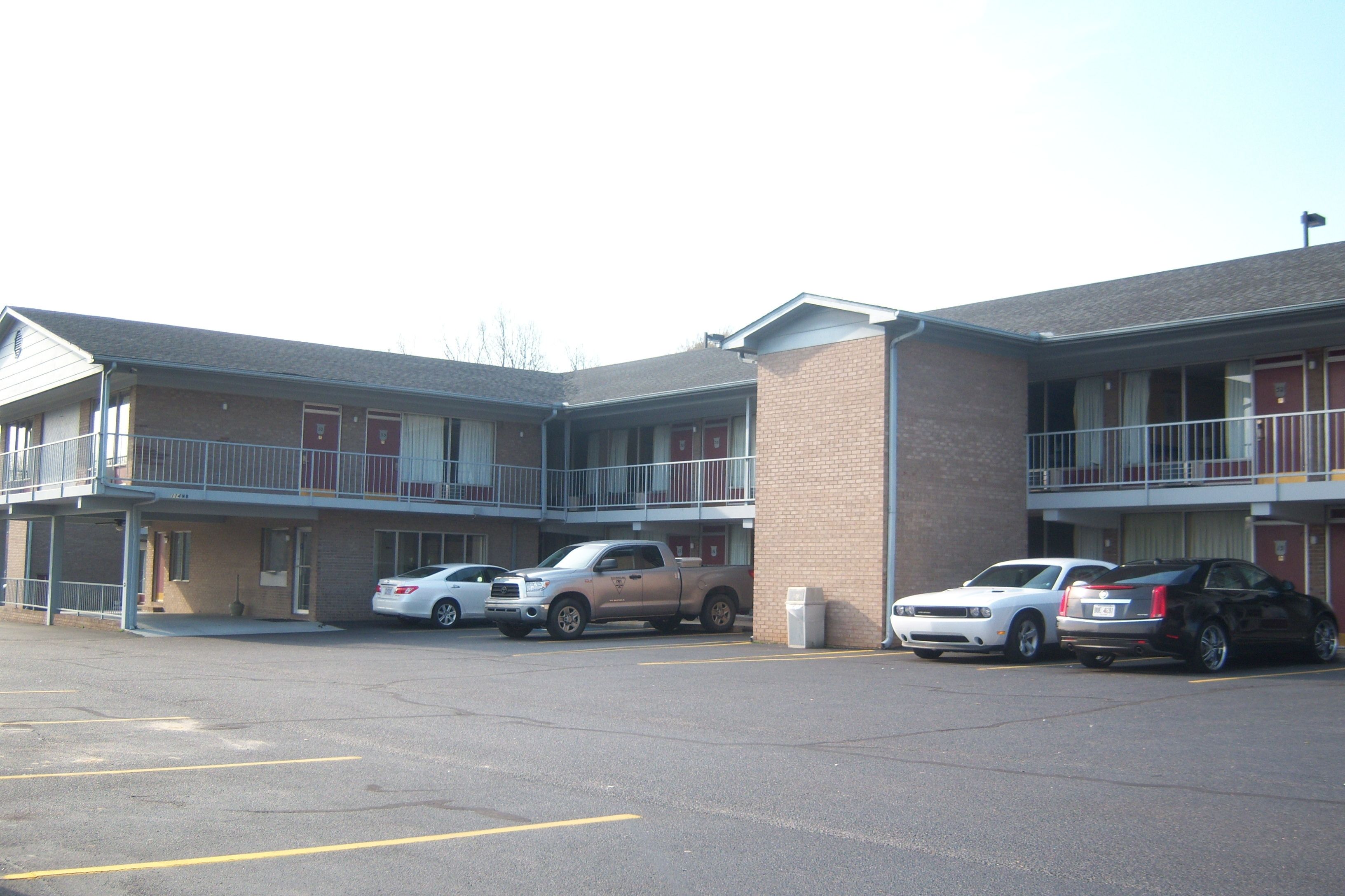 A motel with a parking lot, multiple rooms, and a small outdoor area.