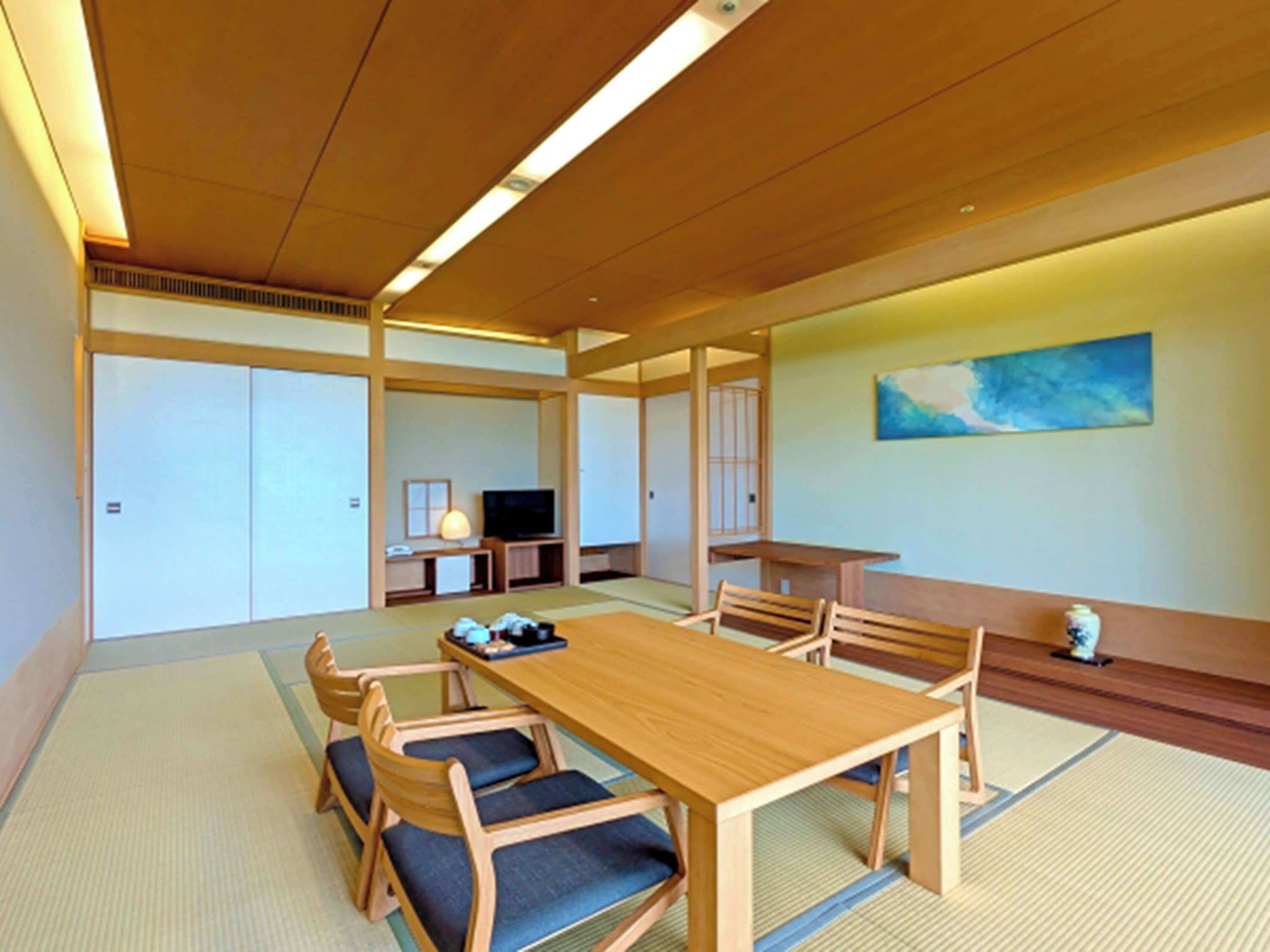 Ein traditioneller japanischer Raum mit Tatami-Boden, einem niedrigen Holztisch und integrierten Sitzgelegenheiten.