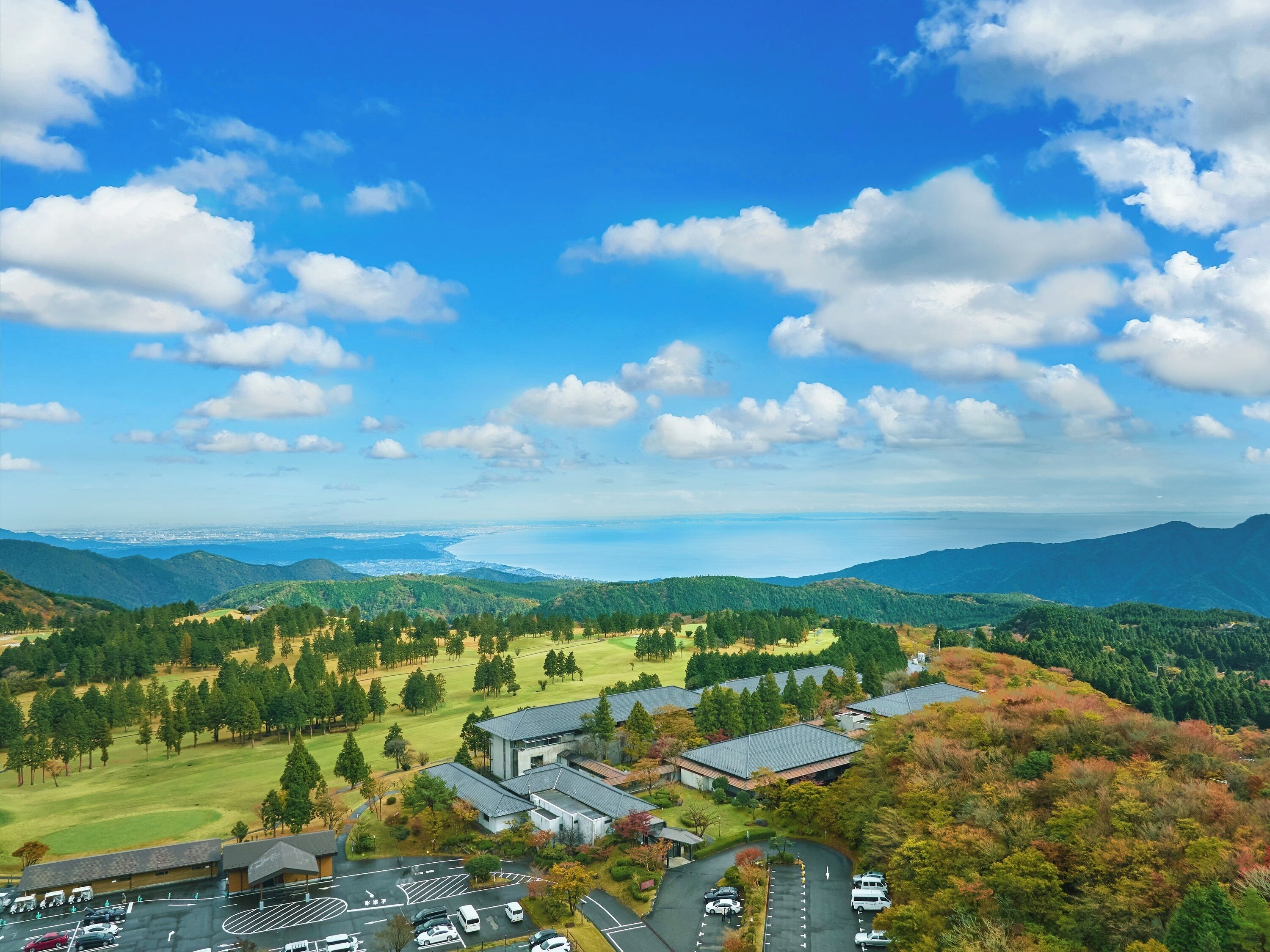 Et panorama over et campus med flere bygninger, parkeringsområder og grønne bakker i det omkringliggende landskab.