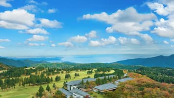 Et panorama over et campus med flere bygninger, parkeringsområder og grønne bakker i det omkringliggende landskab.