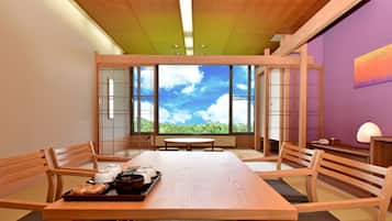 Una habitación tradicional japonesa con una mesa de madera, sillas y vista al cielo a través de amplios ventanales.