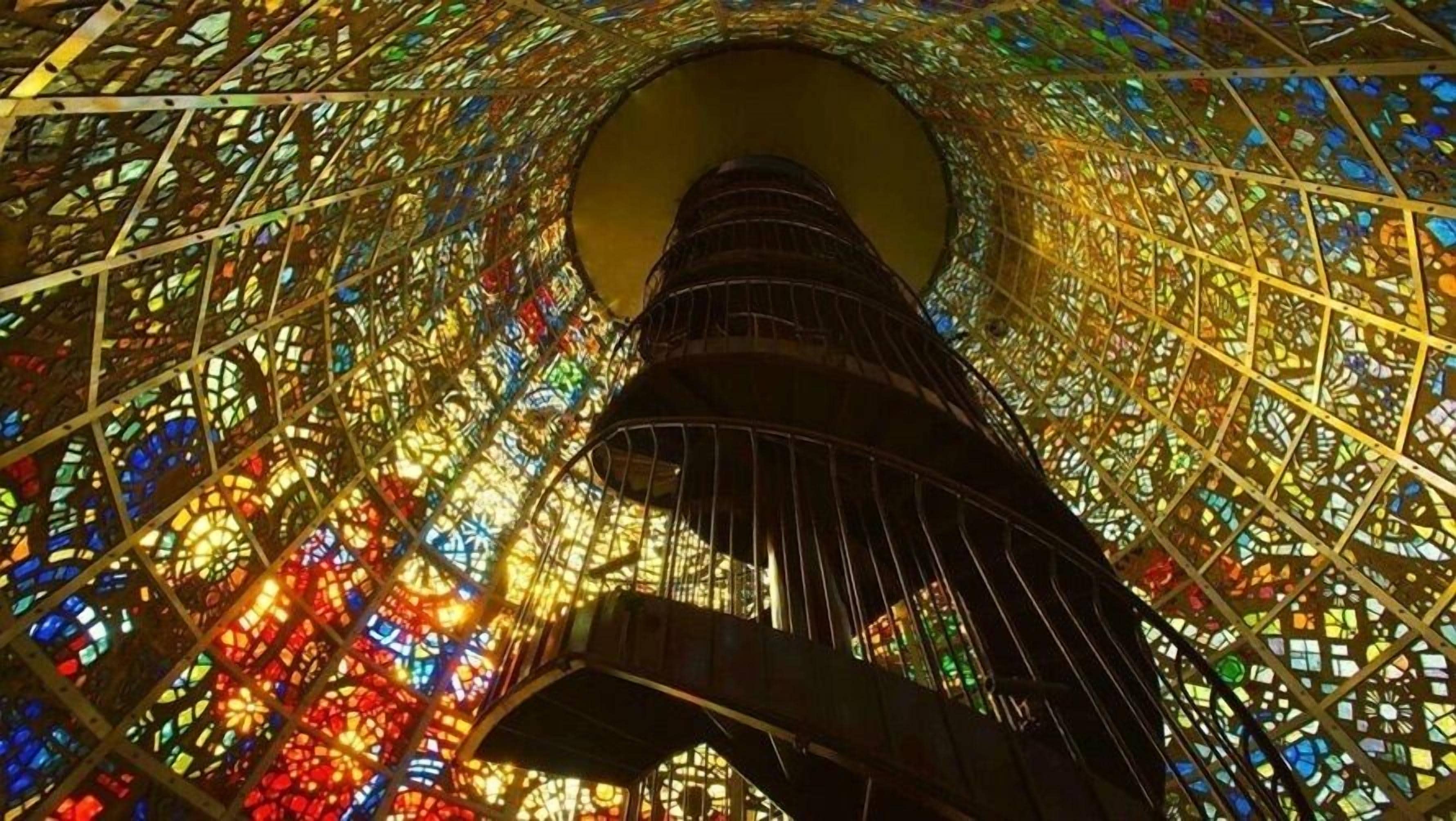 A close-up of a building's interior with a complex, colorful stained glass design.