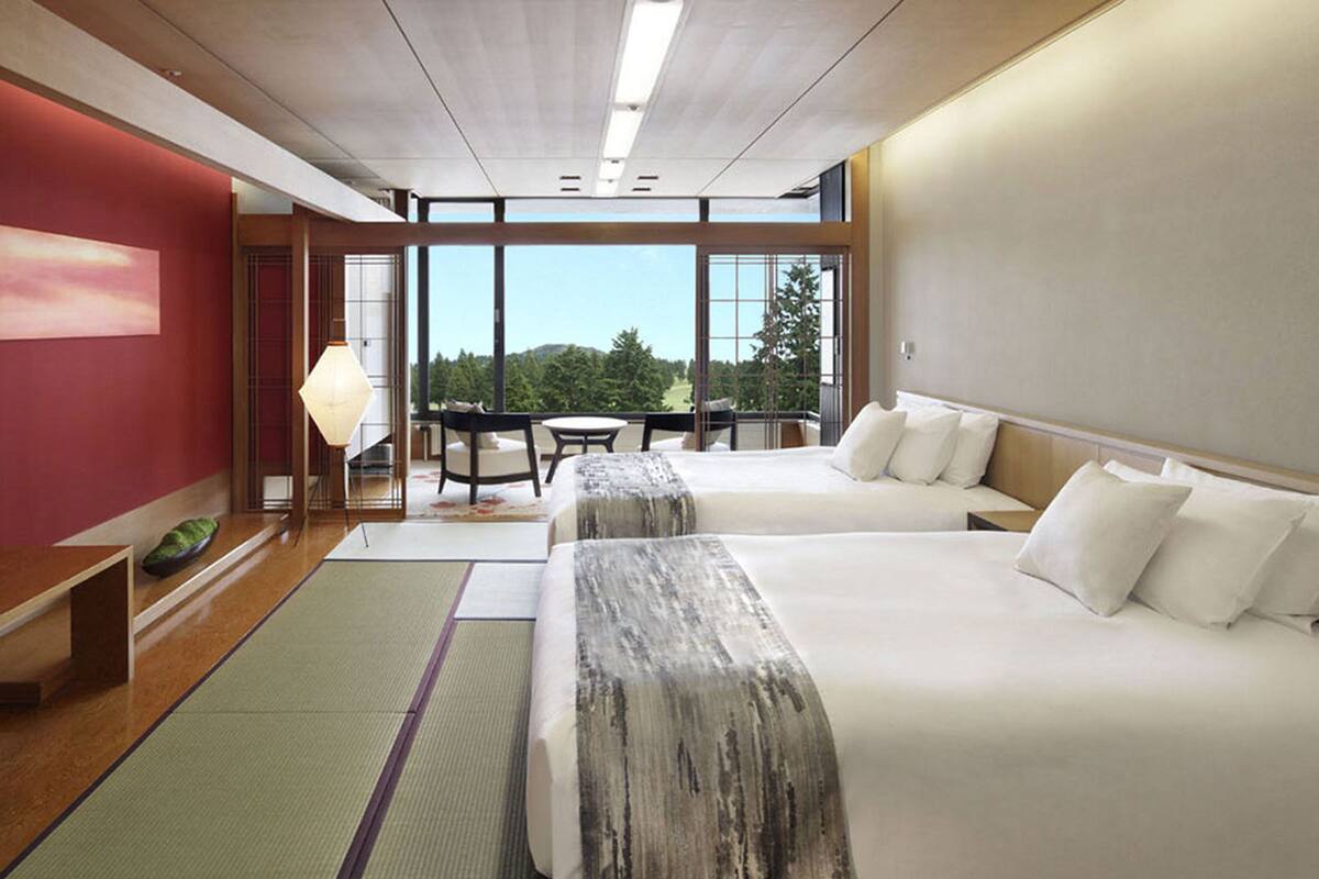 A hotel room with two beds, a large window, and a view of the outdoors.