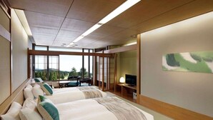 Habitación de hotel con dos camas, televisor y un amplio ventanal con vistas al exterior.