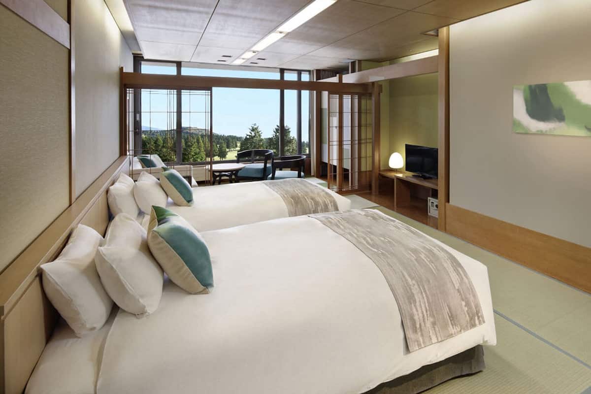 Une chambre d’hôtel avec deux lits, une télévision, un bureau et une vue sur l’extérieur.